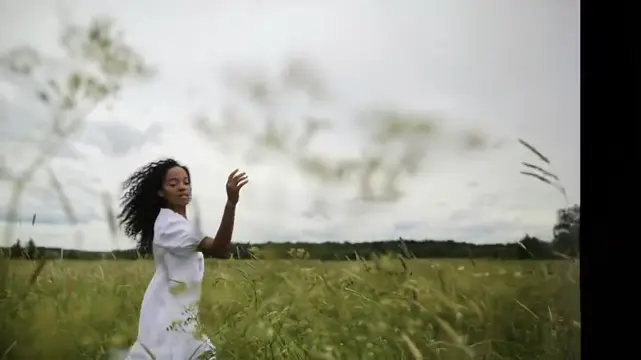 A woman in a flowing white dress stands in a green meadow.